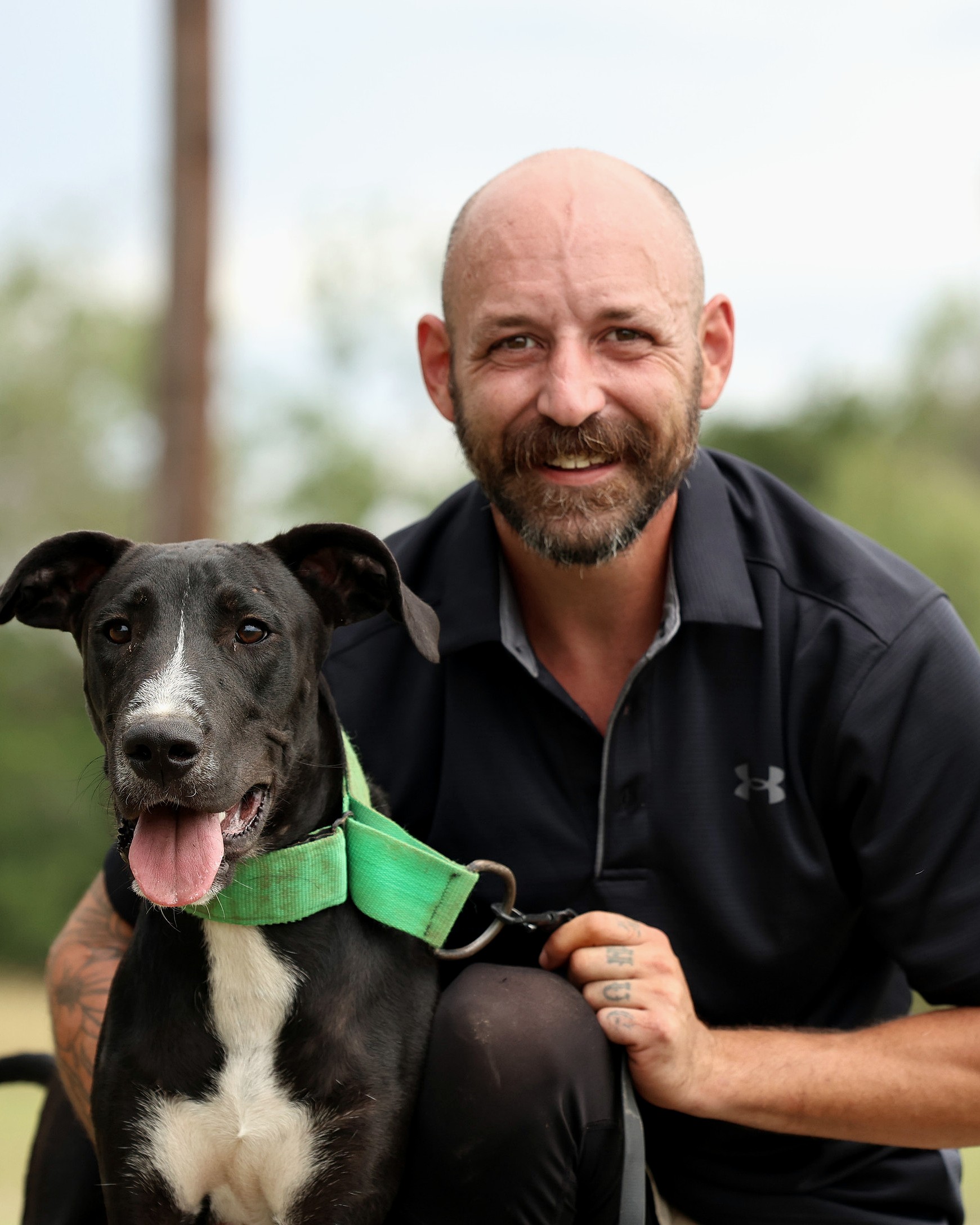 Ryan smiling warmly with a black and white dog close to his shoulder.