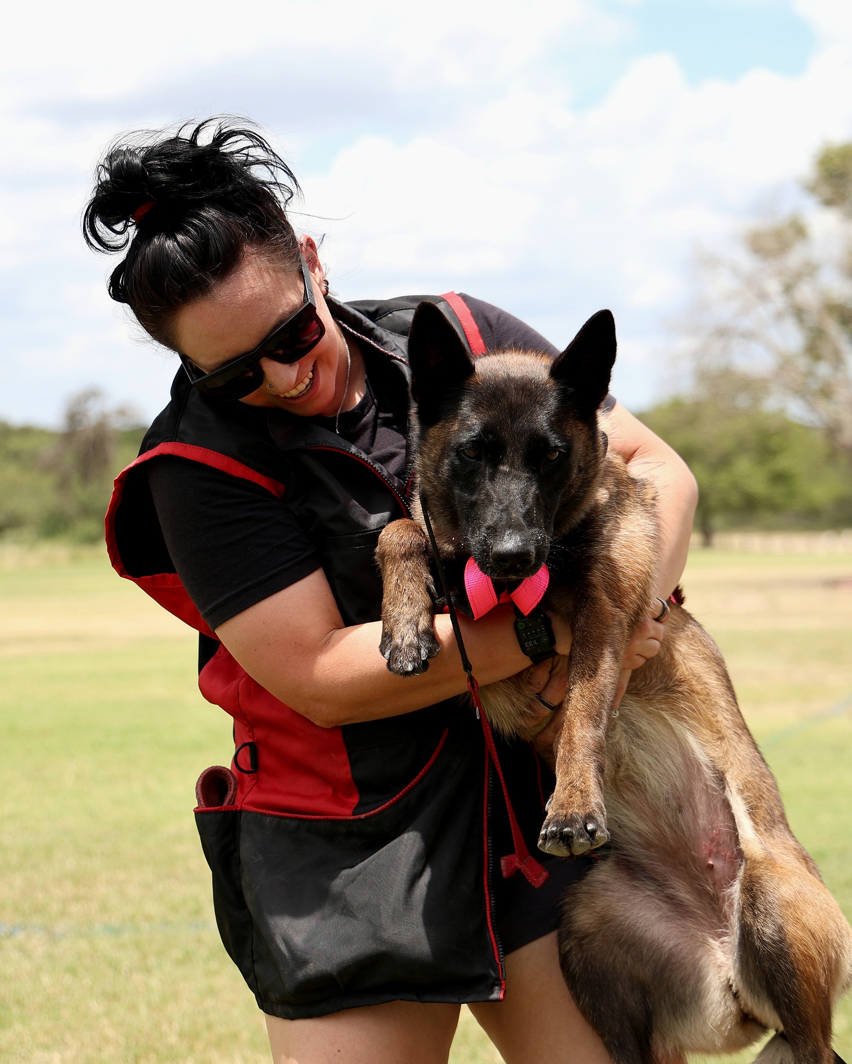 Handler warmly holding a working dog just after a training session.